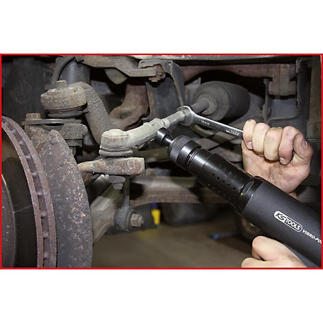 Mechaniker schraubt mit Werkzeug an Autoteil. Detailaufnahme von Hand und Werkzeug.